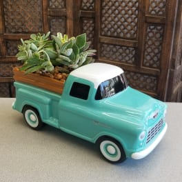 Succulents arranged in a turquoise ceramic truck planter