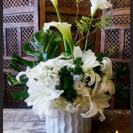 White calla lilies and lilies arranged in a white vase