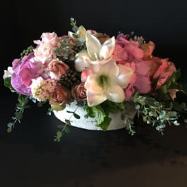 Low floral arrangement with pink roses and white lilies in a white container
