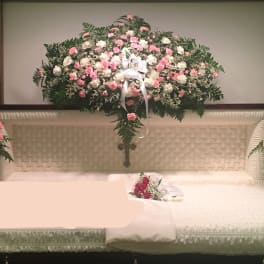 White casket with pink and white floral sprays