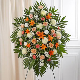 Large standing floral spray with peach roses, orange lilies, and white blooms