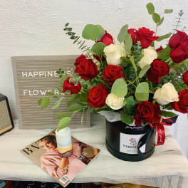 Red and white roses in a black hatbox with eucalyptus