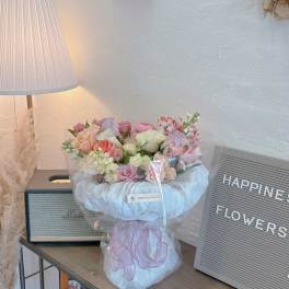 Pastel bouquet of roses and alstroemeria wrapped in white tulle