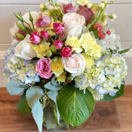 Mixed pastel bouquet with roses, hydrangeas, and carnations in a glass vase