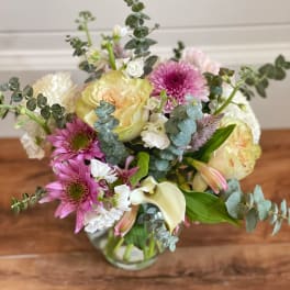 Mixed bouquet of pink and cream flowers in a glass vase