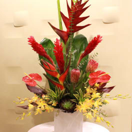 Tropical floral arrangement in a white vase with red and yellow blooms