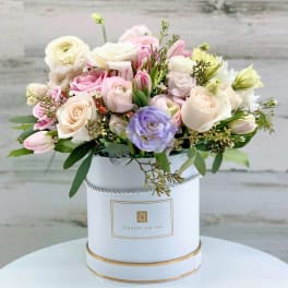 Pastel bouquet of roses and tulips in a white hatbox