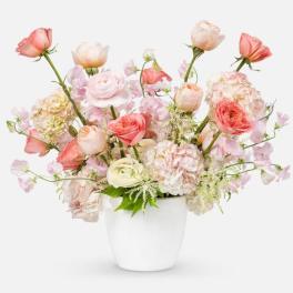 Pastel bouquet of roses and ranunculus in a white vase