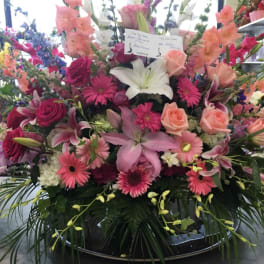 Large mixed flower arrangement with lilies, roses, and gerbera daisies in a low container