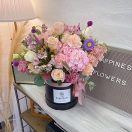 Pink and peach flower arrangement in a black hat box