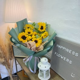 Bouquet of yellow sunflowers wrapped in green paper