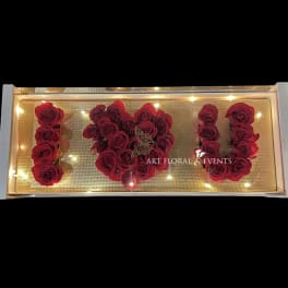 Red roses arranged to spell "I U" in a lit display box