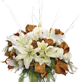 White lilies and roses arranged in a glass vase with copper ribbon and branches