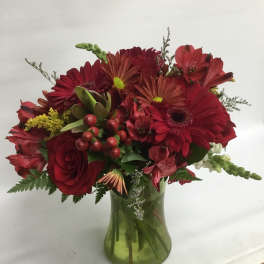 Red mixed flower bouquet in a green glass vase