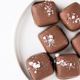 Six square milk chocolates sprinkled with coarse salt on a white plate