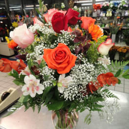 Mixed bouquet of roses and white filler flowers in a clear glass vase