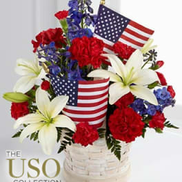 Red, white, and blue floral arrangement in a basket with small American flags