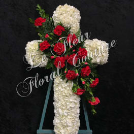 White floral cross with red carnations on an easel