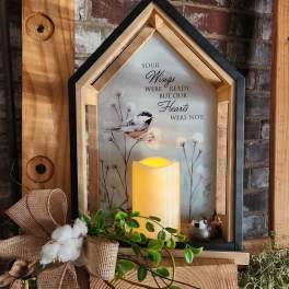 House-shaped memorial lantern with a bird print and glowing candle