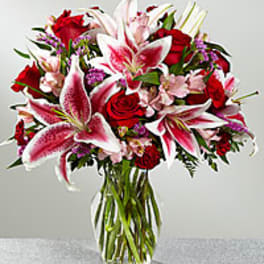 Bouquet of red roses and pink lilies in a clear glass vase
