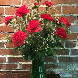 Red carnations in a green glass vase