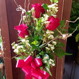 Red roses in a clear glass vase with a pink ribbon bow