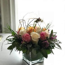 Pink and white roses arranged in a square glass vase