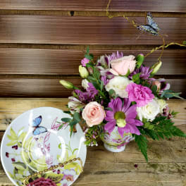 Bouquet of pink, white, and purple flowers in a decorative teacup vase