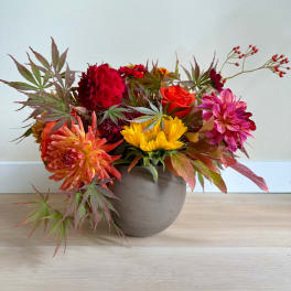 Colorful mixed flower arrangement in a round gray vase