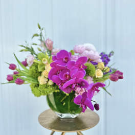 Purple orchids and mixed pastel flowers in a glass vase