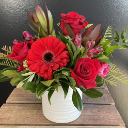 Red roses and a gerbera daisy in a white vase