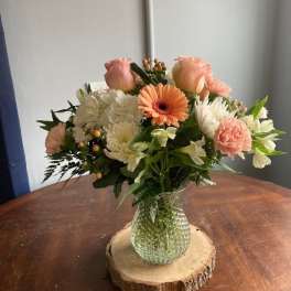 Mixed bouquet in a glass vase on a wood slice