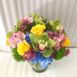 Colorful bouquet of roses, orchids, and hydrangeas in a glass vase