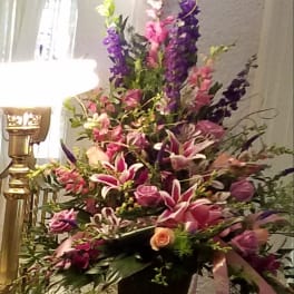 Tall floral arrangement in a black container with pink, purple, and white blooms