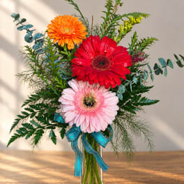 Bouquet of red, pink, and orange gerbera daisies in a clear glass vase