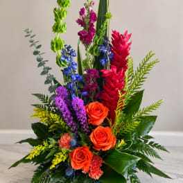 Tall multicolor floral arrangement with orange roses and bright tropical blooms