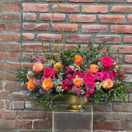 Arrangement of pink and orange roses in a gold vase