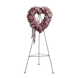 Heart-shaped pink rose wreath on a metal stand with ribbon