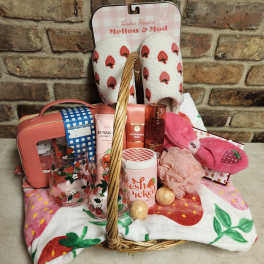 Gift basket with strawberry-themed slippers, socks, and bath items