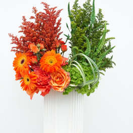 Orange flowers and green foliage arranged in a white vase