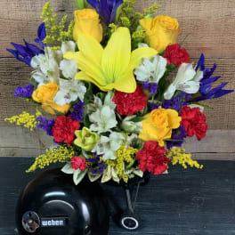 Bright mixed bouquet with yellow lilies, roses, and white alstroemeria in a black vase
