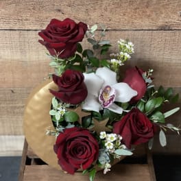 Bouquet of red roses and white orchids with greenery in a gold box