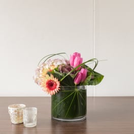Pink tulips and gerbera daisies arranged in a glass vase