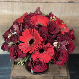 Bouquet of red roses and gerbera daisies in a low container