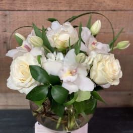 White roses and orchids arranged in a glass vase