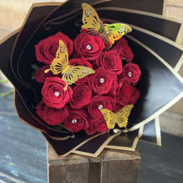 Bouquet of red roses wrapped in black paper with gold butterfly accents