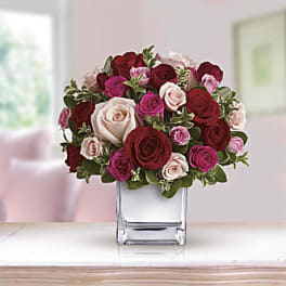 Bouquet of red, pink, and white roses in a clear glass vase