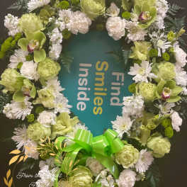 Green and white floral wreath with a bright ribbon bow