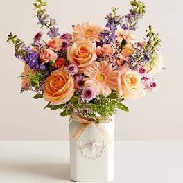 Peach roses and purple flowers in a white vase