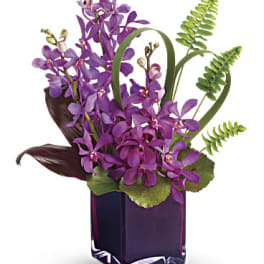 Purple orchid arrangement in a dark glass vase